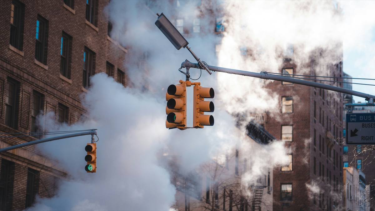 Traffic lights glowing through street steam between brick buildings in New York