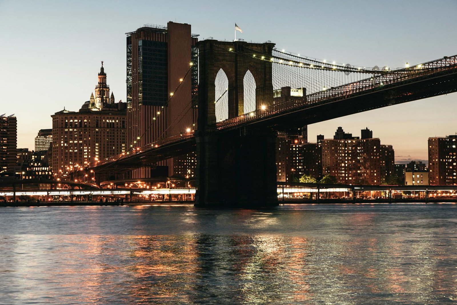 The Brooklyn Bridge at dusk with the city lights behind it