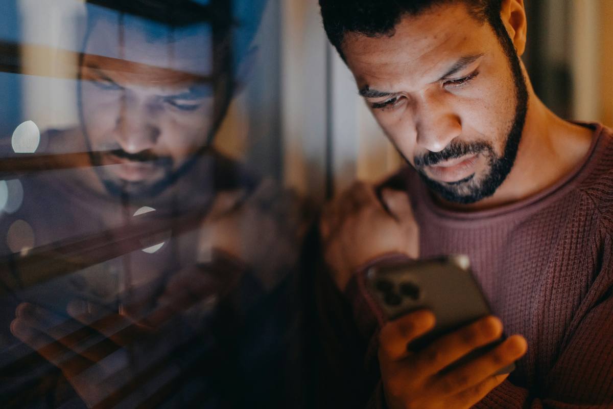 Man reading his phone by a window late at night