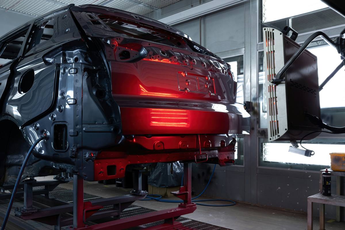 Car body curing under red lights in a repair-shop paint booth