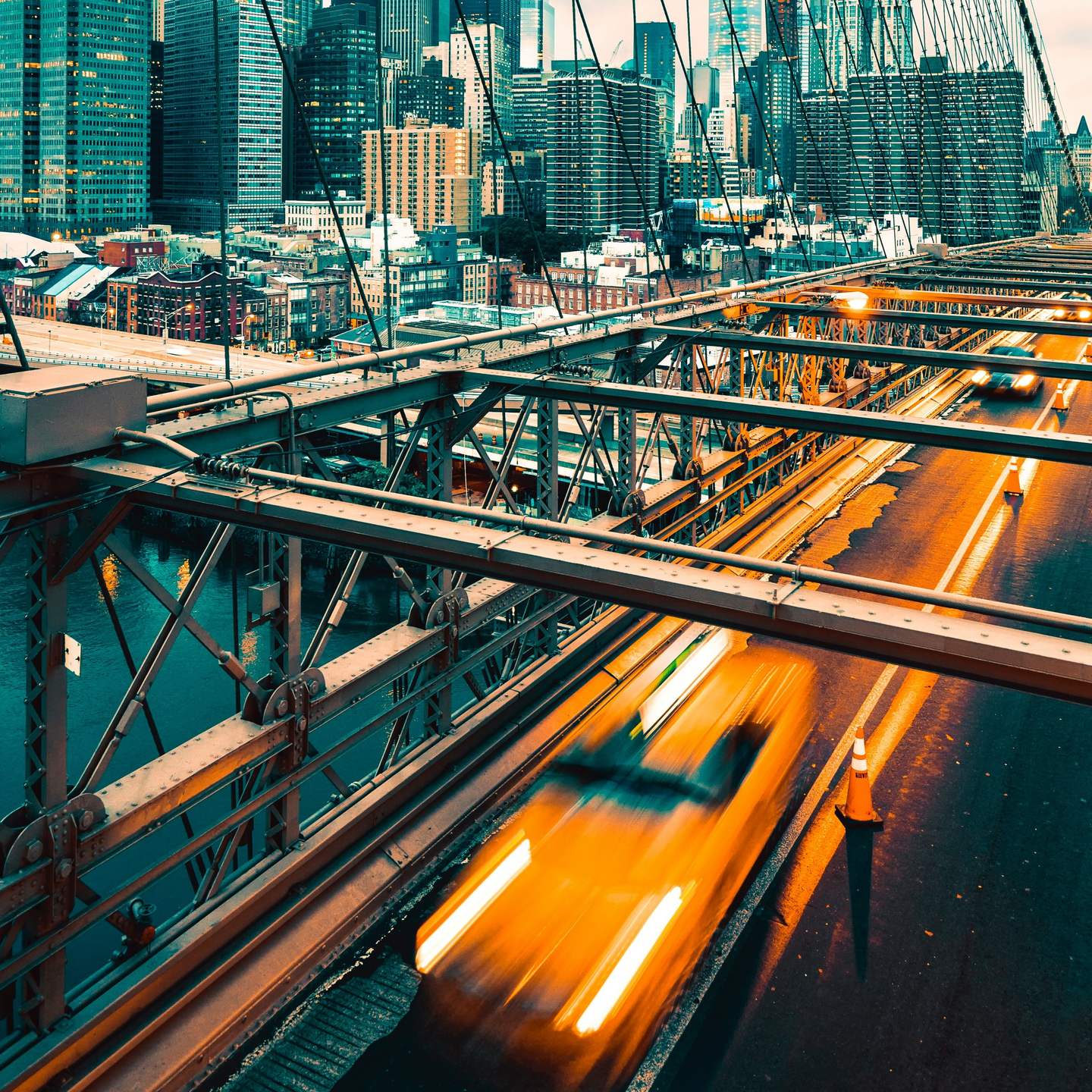Yellow cab crossing the Brooklyn Bridge deck at dusk