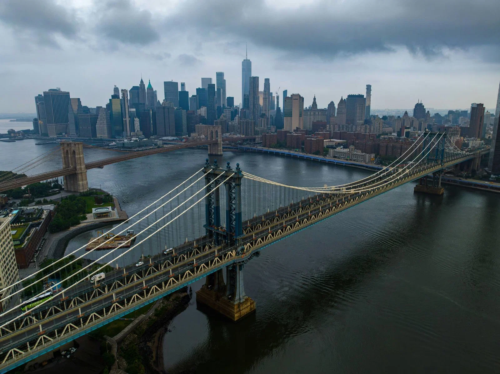 Aerial view of the Manhattan and Brooklyn Bridges over the East River under moody clouds
