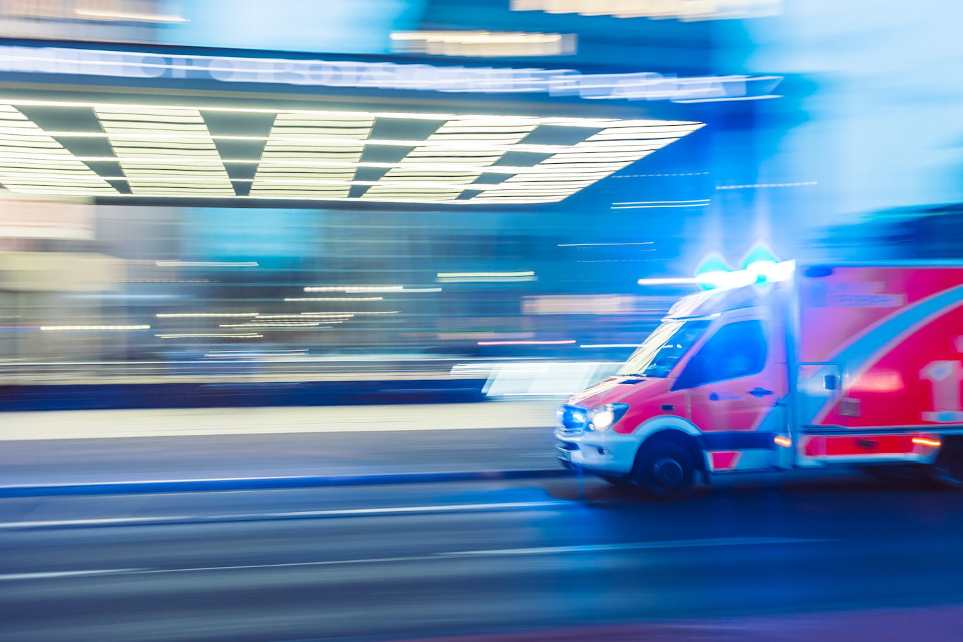 Ambulance speeding past city buildings at night, lights on