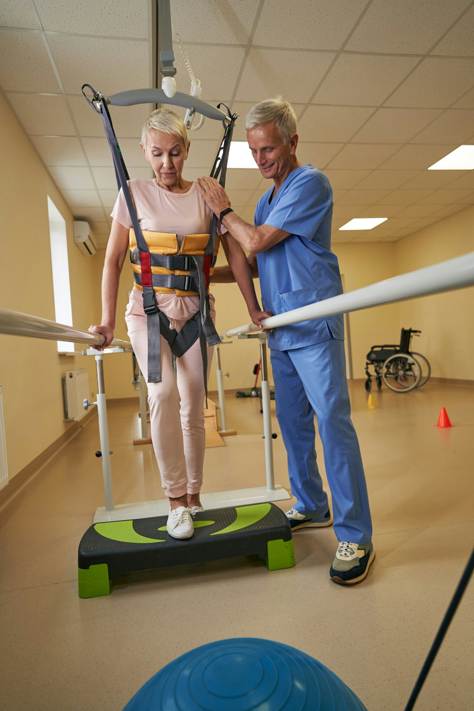 Patient relearning to walk in a support harness between parallel bars